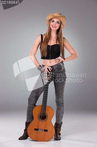 Image of The beautiful girl in a cowboy\'s hat and acoustic guitar.