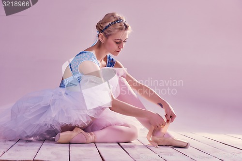 Image of Professional ballerina putting on her ballet shoes.