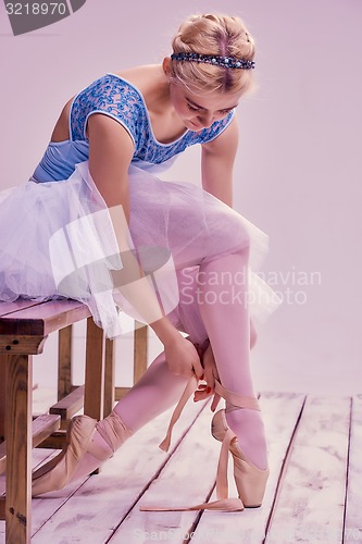 Image of Professional ballerina putting on her ballet shoes.