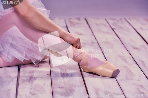 Image of Professional ballerina putting on her ballet shoes.