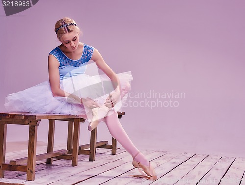 Image of Professional ballerina putting on her ballet shoes.