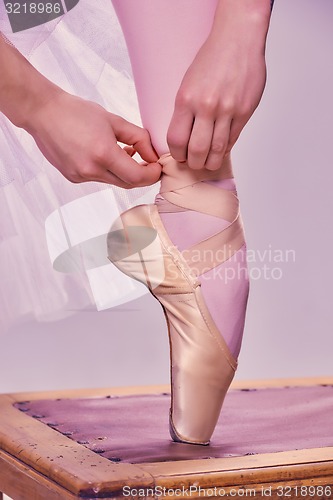 Image of Professional ballerina putting on her ballet shoes.