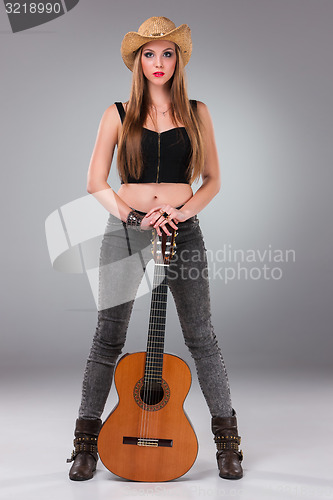 Image of The beautiful girl in a cowboy\'s hat and acoustic guitar.