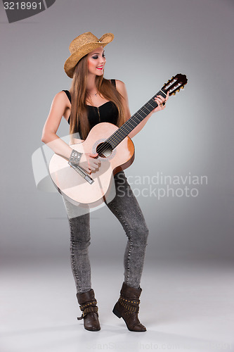 Image of The beautiful girl in a cowboy\'s hat and acoustic guitar.