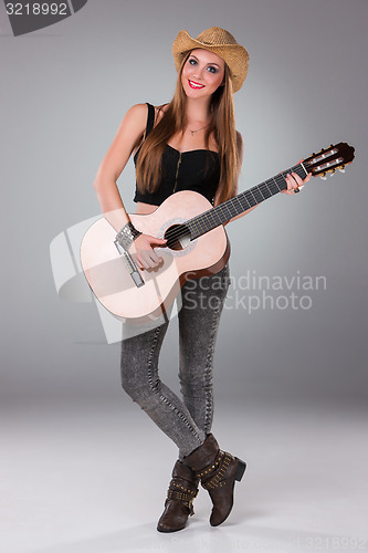 Image of The beautiful girl in a cowboy\'s hat and acoustic guitar.