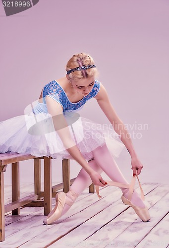 Image of Professional ballerina putting on her ballet shoes.