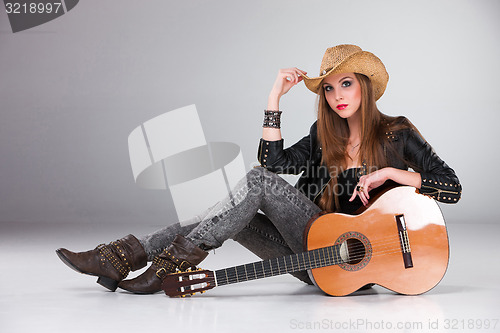 Image of The beautiful girl in a cowboy\'s hat and acoustic guitar.