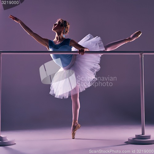 Image of classic ballerina posing at ballet barre