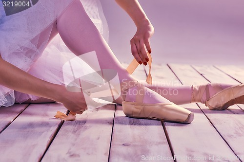 Image of Professional ballerina putting on her ballet shoes.