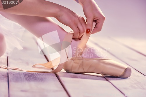Image of Professional ballerina putting on her ballet shoes.