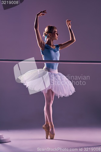 Image of classic ballerina posing at ballet barre