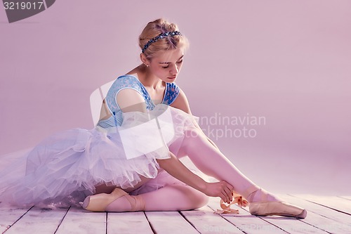 Image of Professional ballerina putting on her ballet shoes.