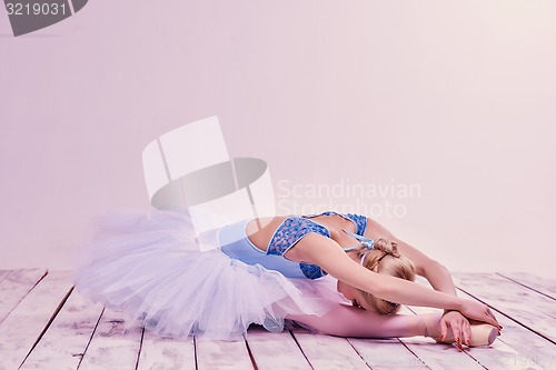 Image of Tired ballet dancer lying on the wooden floor 