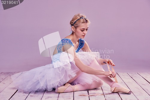 Image of Professional ballerina putting on her ballet shoes.