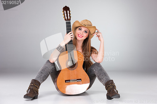 Image of The beautiful girl in a cowboy\'s hat and acoustic guitar.