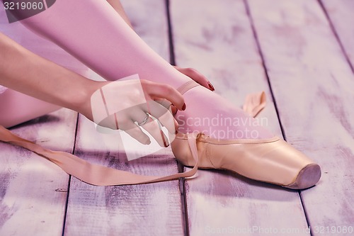 Image of Professional ballerina putting on her ballet shoes.