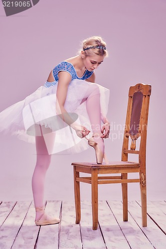 Image of Professional ballerina putting on her ballet shoes.