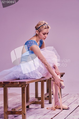 Image of Professional ballerina putting on her ballet shoes.