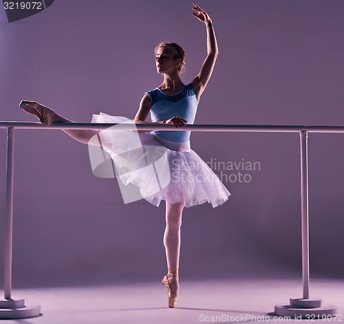 Image of classic ballerina posing at ballet barre