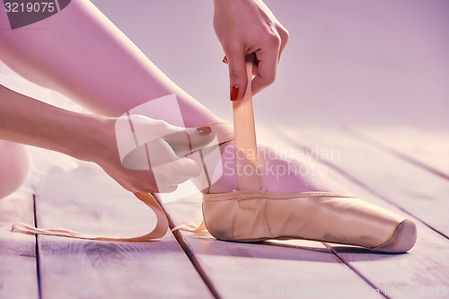 Image of Professional ballerina putting on her ballet shoes.