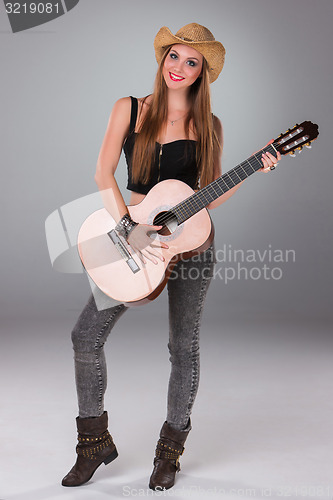 Image of The beautiful girl in a cowboy\'s hat and acoustic guitar.