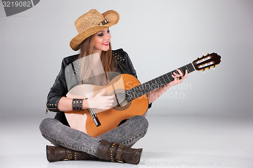 Image of The beautiful girl in a cowboy\'s hat and acoustic guitar.