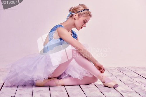 Image of Professional ballerina putting on her ballet shoes.