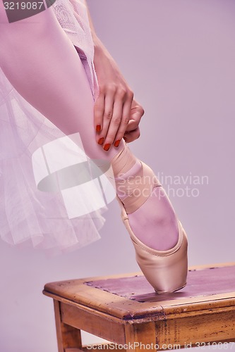 Image of Professional ballerina putting on her ballet shoes.