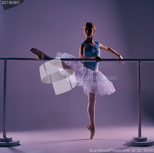 Image of classic ballerina posing at ballet barre