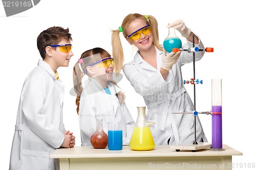 Image of Teens and teacher of chemistry at  lesson making experiments