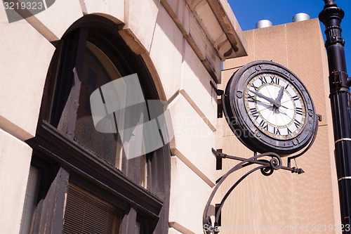 Image of Community Clock Mounted on Building Close Corner Sidewalk