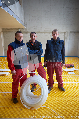 Image of workers installing underfloor heating system