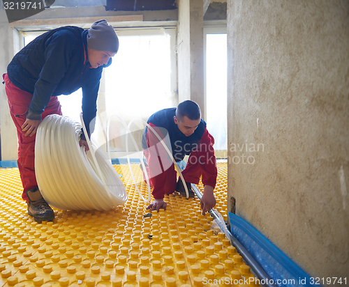 Image of workers installing underfloor heating system