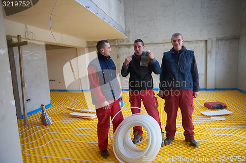 Image of workers installing underfloor heating system