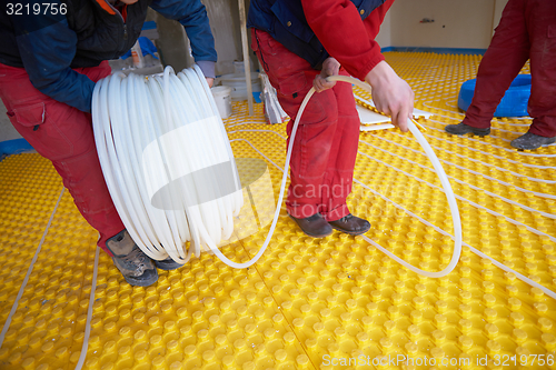 Image of workers installing underfloor heating system