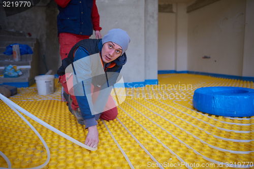 Image of workers installing underfloor heating system