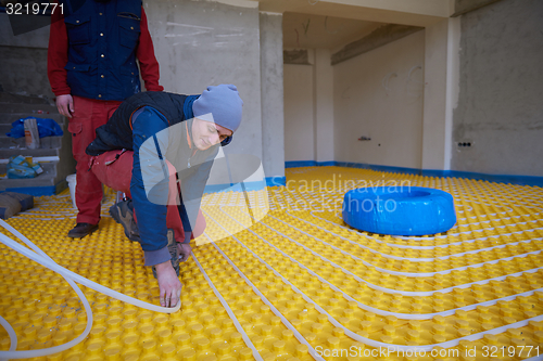 Image of workers installing underfloor heating system