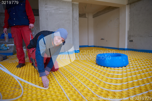 Image of workers installing underfloor heating system