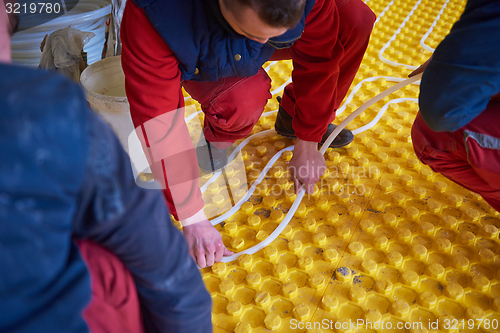 Image of workers installing underfloor heating system