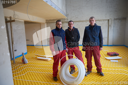 Image of workers installing underfloor heating system