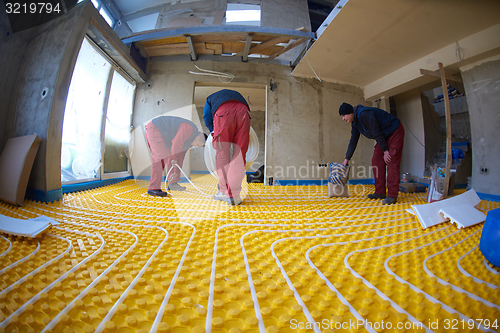 Image of workers installing underfloor heating system