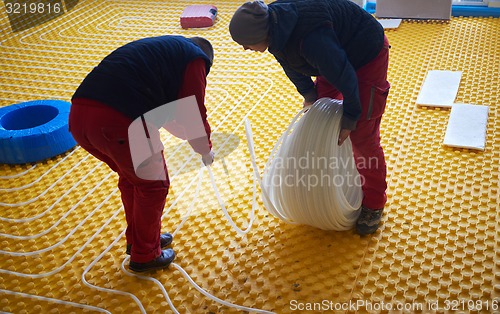 Image of workers installing underfloor heating system