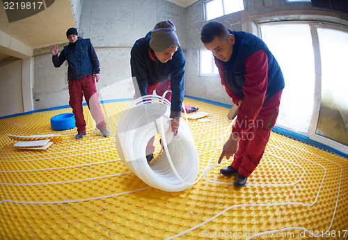 Image of workers installing underfloor heating system