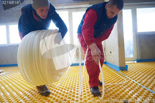 Image of workers installing underfloor heating system