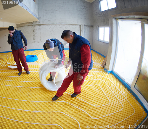 Image of workers installing underfloor heating system