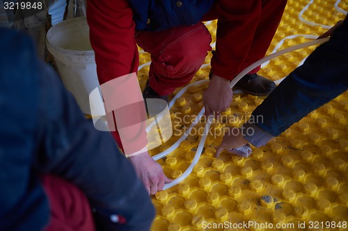 Image of workers installing underfloor heating system