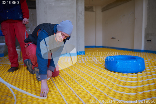 Image of workers installing underfloor heating system