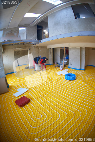 Image of workers installing underfloor heating system