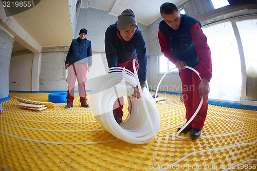 Image of workers installing underfloor heating system