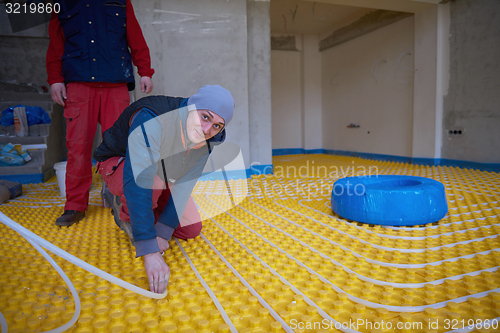 Image of workers installing underfloor heating system